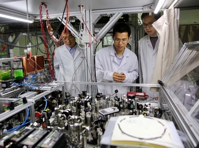 2017年5月3日,中国科学技术大学陆朝阳教授(中)和学生们在中国科学院量子信息和量子科技创新研究院上海实验室检查光量子计算机的运行情况。(图源:新华社)